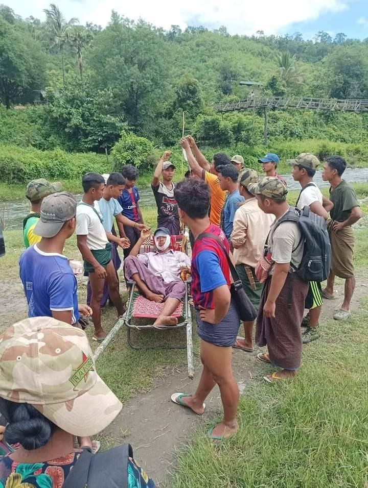 (ဒဏ်ရာရရဲဘော်အား ထမ်းစင်ဖြင့် သယ်ဆောင်လာစဥ်။ဓာတ်ပုံ- The Youth Force -Saw&Kyaukhtu)