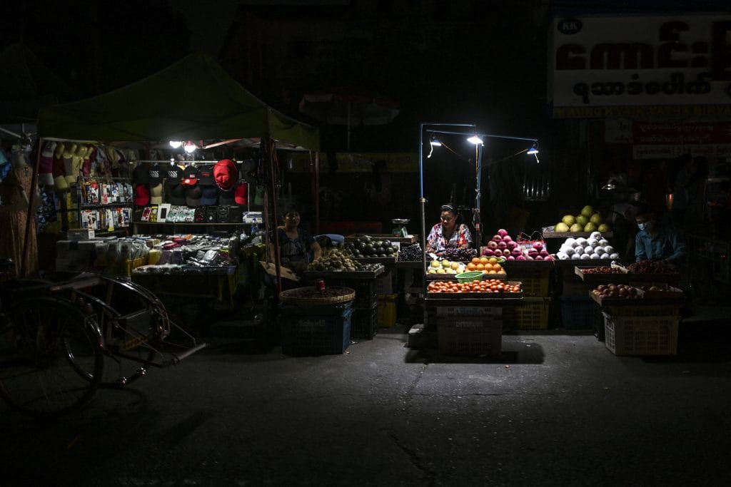 (စီးပွား​ရေးမြို့​တော်ရန်ကုန်တွင် မီးပျက်၍ မီးထွန်း​ဈေး​ရောင်း​နေ​သော ​ဈေးသည်အချို့ ။ ။ဓါတ်ပုံ-AFP)