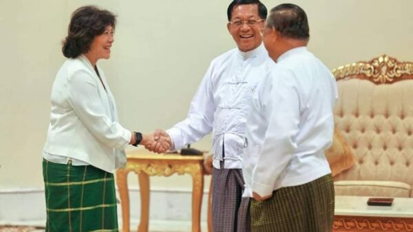 ပြည်သူ​ထောင်ချီ​စေ​စေခဲ့​သော အာဏာသိမ်း​ခေါင်း​ဆောင်နှင့်လက်ချင်းဆွဲနှုတ်ဆက်​နေ​သော ကုလအတွင်း​ရေးမှူးချုပ်၏ မြန်မာနိုင်ငံဆိုင်ရာအထူးကိုယ်စားလှယ်။ ဓါတ်ပုံ-စကစ