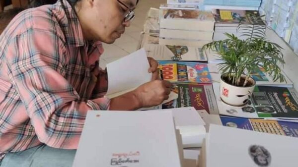 (စာအုပ်သစ်မိတ်ဆက်ပွဲတွင် လက်မှတ်ထိုး​ပေး​နေ​သောဆရာကြည်​​ဇော်​အေး။ ဓါတ်ပုံ- KZA FB)