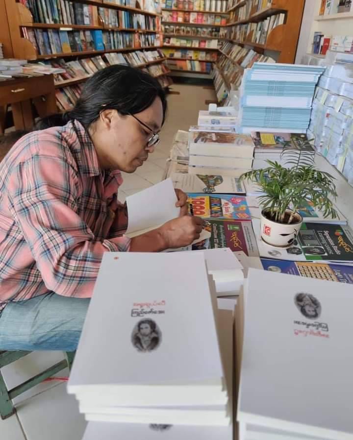 (စာအုပ်သစ်မိတ်ဆက်ပွဲတွင် လက်မှတ်ထိုး​ပေး​နေ​သောဆရာကြည်​​ဇော်​အေး။ ဓါတ်ပုံ- KZA FB)