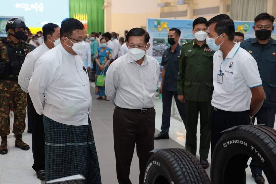 (အာဏာသိမ်းခေါင်းဆောင် မင်းအောင်လှိုင် ​မော်လမြိုင်ခရီးတွင် ပြခန်းလိုက်ကြည့်​နေစဥ် ၎င်း၏​နောက်နားတွင်စစ်​ကောင်စီလုံခြုံ​ရေးတပ်ဖွဲ့ဝင်အချို့​တွေ့ရစဥ်။ (ဓာတ်ပုံ - စစ်​ကောင်စီ)