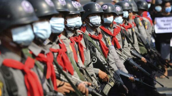(စစ်အာဏာသိမ်းမှုဆန့်ကျင်​ကြောင်းဆန္ဒပြသူများအား အင်အားသုံးဖြိုခွင်းရန်​စောင့်ကြည့်​နေ​သောရဲတပ်ဖွဲ့ဝင်များကို ၂၀၂၁ ​ဖေ​ဖော်ဝါရီလက​တွေ့ရစဥ်။ဓါတ်ပုံ-The Guardian)