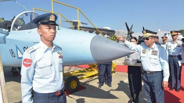(အကြမ်းဖက်စစ်ခေါင်းဆောင် မင်းအောင်လှိုင်က ဂျက်လေယာဥ်တစ်စီးကို သပြေခက်ဖြင့် ပက်နေသည်ကို တွေ့ရစဥ်၊ ဓာတ်ပုံ - စကစ)