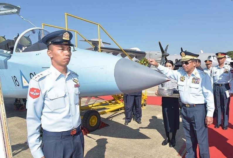(အကြမ်းဖက်စစ်ခေါင်းဆောင် မင်းအောင်လှိုင်က ဂျက်လေယာဥ်တစ်စီးကို သပြေခက်ဖြင့် ပက်နေသည်ကို တွေ့ရစဥ်၊ ဓာတ်ပုံ - စကစ)