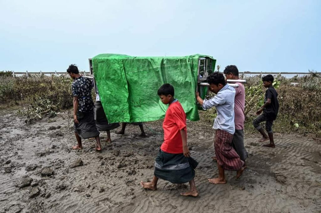 (စစ်တွေမြို့နယ်က မိုခါမုန်တိုင်းဒဏ်ခံခဲ့ရတဲ့ ဂျိုဟင်ဂျာ မွတ်စလင် ဒုက္ခသည်စခန်းတွေနဲ့ ကျေးရွာတွေမှာ မုန်တိုင်းကြောင့် အပျက်အစီးတွေ ၊ သေဆုံးထိခိုက်ပျက်စီးမှုကောက်ယူပြီးတဲ့ရွာစာရင်းနဲ့ သေဆုံးသွားသူတွေရဲ့ နာရေးပြုလုပ်ဖို့ ပြင်ဆင်နေစဥ်။ဓါတ်ပုံ- Getty Images ၊CJ)
