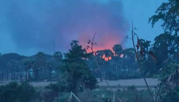 (ညောင်ပင်ကြီးကျေးရွာရဲစခန်း၌ တိုက်ပွဲဖြစ်ပွားနေသည်ကို အဝေးမှမြင်တွေ့ရစဥ်နှင့် စစ်တပ်ရဟတ်ယာဥ်တစ်စီး။ဓာတ်ပုံ-Aung Khant Zaw)