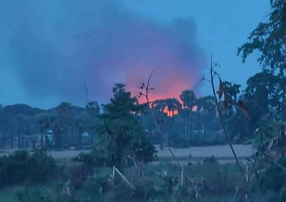 (ညောင်ပင်ကြီးကျေးရွာရဲစခန်း၌ တိုက်ပွဲဖြစ်ပွားနေသည်ကို အဝေးမှမြင်တွေ့ရစဥ်နှင့် စစ်တပ်ရဟတ်ယာဥ်တစ်စီး။ဓာတ်ပုံ-Aung Khant Zaw)