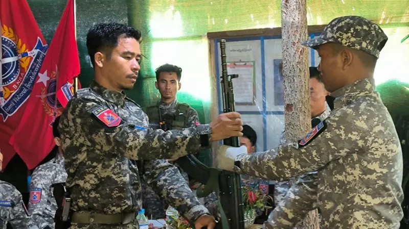 (ဗမာအမျိုးသားတော်လှန်ရေးတပ်မတော် (BNRA) ခေါင်းဆောင် ဗိုလ်နဂါးက အပတ်စဥ် - ၁ သင်တန်းဆင်းပွဲ၌ ရဲဘော်တစ်ဦးအား လက်နက်ပေးအပ်နေစဉ်။ ဓာတ်ပုံ - BNRA)