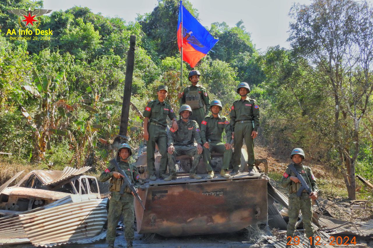 (ဂွမြို့အားသိမ်းပိုက်ပြီးနောက် စစ်ကောင်စီ၏ မီးလောင်နေသော သံချပ်ကာကားပေါ်တွင် အောင်ပွဲခံနေသော AAရဲဘော်များ။ ဓာတ်ပုံ - AA)